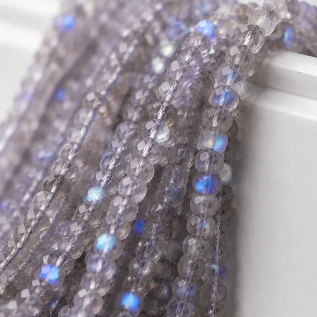 A macro-photographed image of several strands of labradorite gemstones atop a porcelain prop.