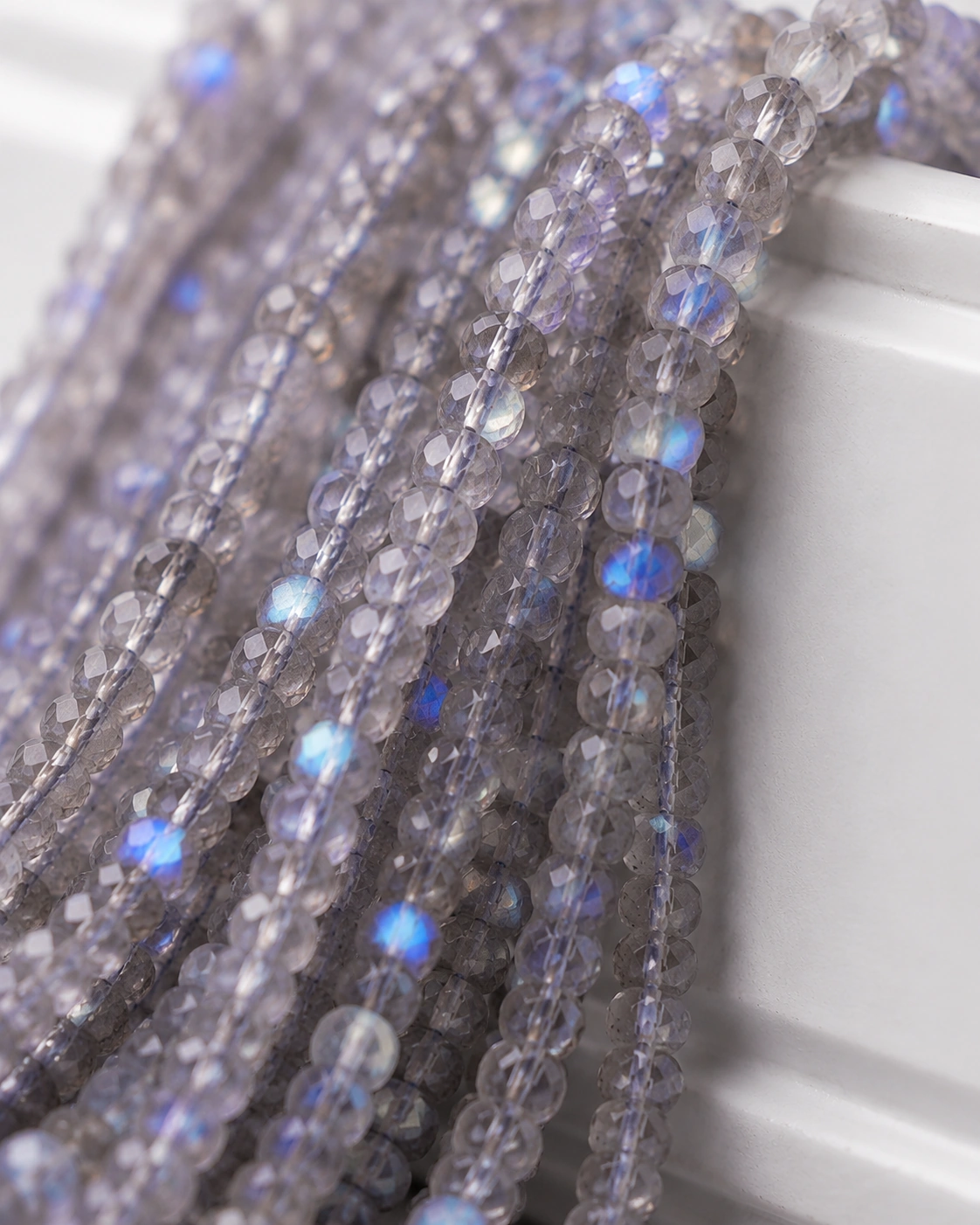 A macro-photographed image of several strands of labradorite gemstones atop a porcelain prop.