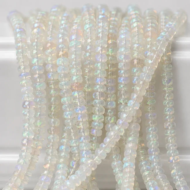 A macro-photographed image of several strands of Ethopian opal gemstones atop a porcelain prop.