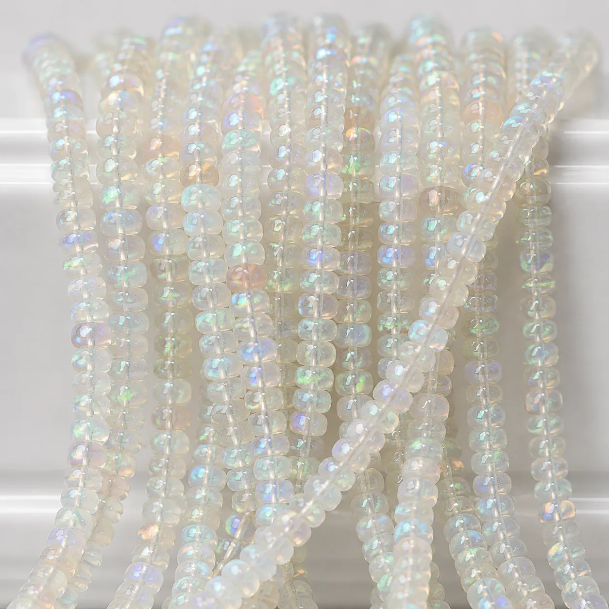 A macro-photographed image of several strands of Ethopian opal gemstones atop a porcelain prop.