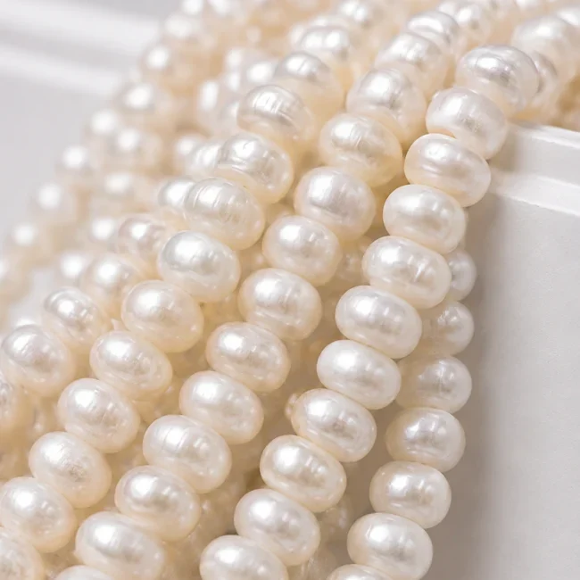A macro-photographed image of several strands of the freshware variety of pearls atop a porcelain prop.