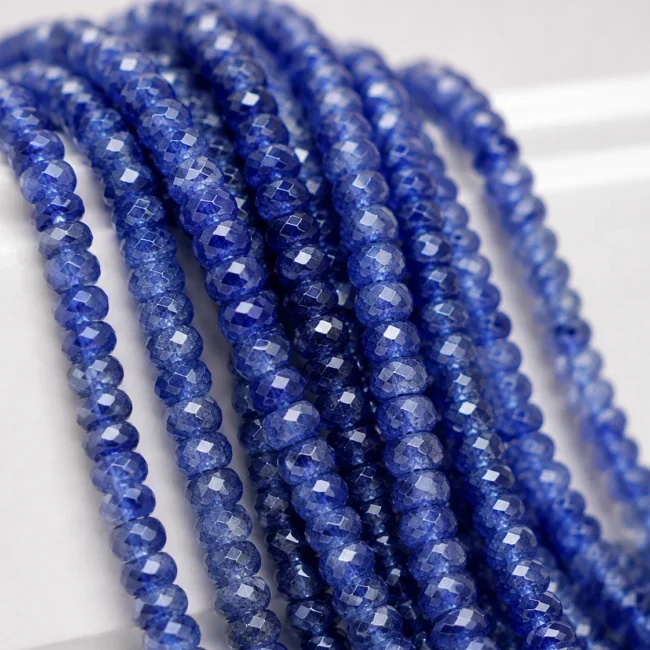 A macro-photographed image of several strands of high quality sapphire gemstone beads atop a porcelain prop.