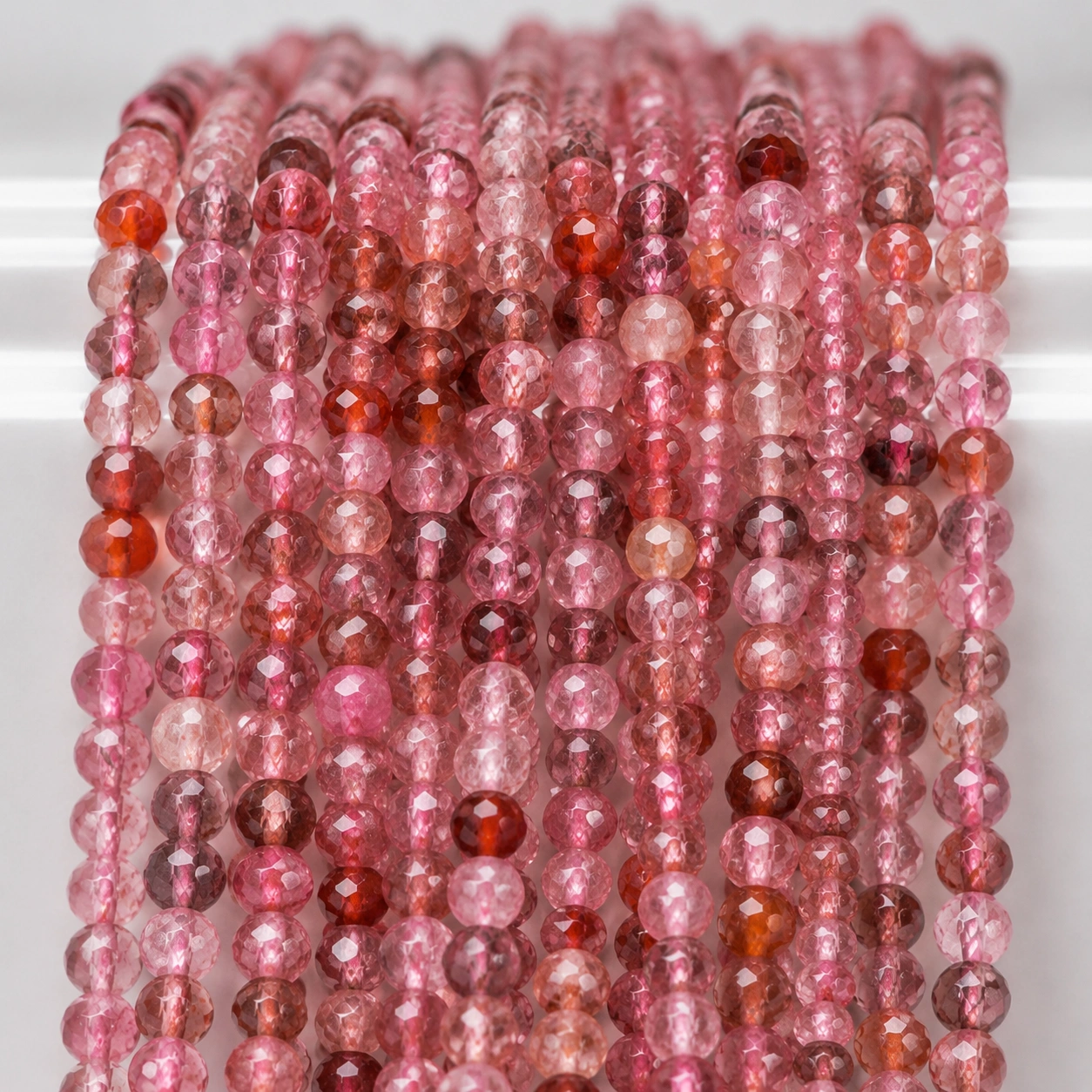 A macro-photographed image of several strands of multi-colored spinel gemstone beads atop a porcelain prop.